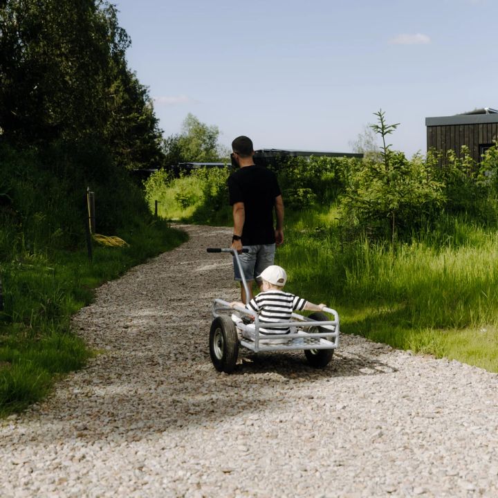 Vater zieht Sohn in Bollerwagen